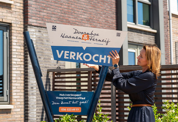 Makelaar met verkoopbord van Doornbos Haanen en Ferneij