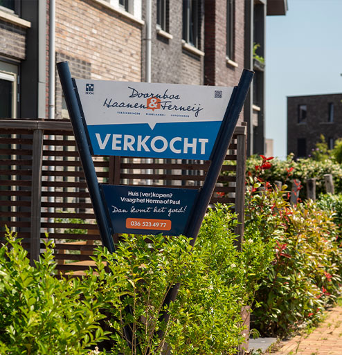 Woning verkocht met bord in de tuin met groen eromheen