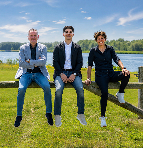 drie makelaars op een hek met water achter hun